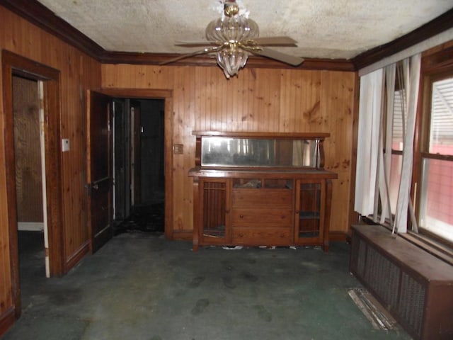 interior space featuring a textured ceiling, ceiling fan, wooden walls, dark colored carpet, and radiator heating unit