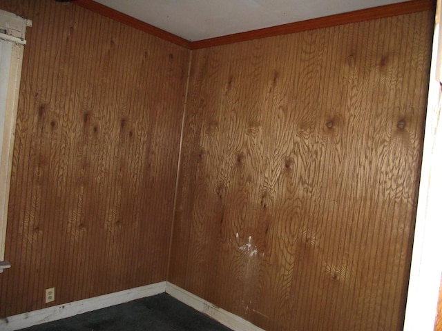 unfurnished room featuring wooden walls and baseboards