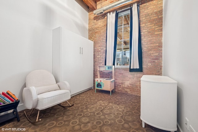 sitting room featuring brick wall and a high ceiling