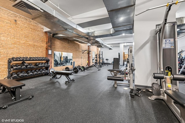 exercise room with visible vents and brick wall