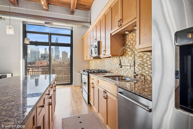 kitchen with a sink, appliances with stainless steel finishes, a city view, light wood-type flooring, and backsplash