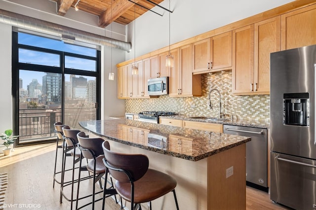 kitchen with a kitchen island, beam ceiling, a sink, appliances with stainless steel finishes, and a city view