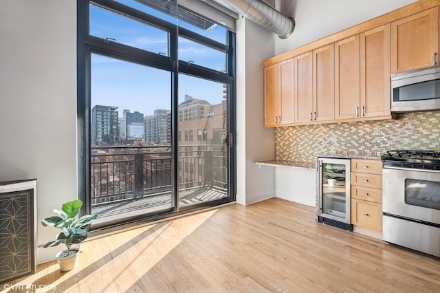 kitchen featuring wine cooler, light brown cabinetry, decorative backsplash, appliances with stainless steel finishes, and a view of city