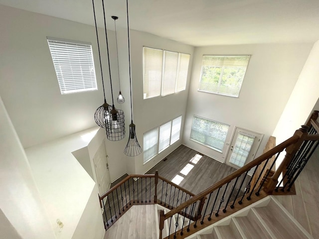 staircase featuring a towering ceiling and wood finished floors