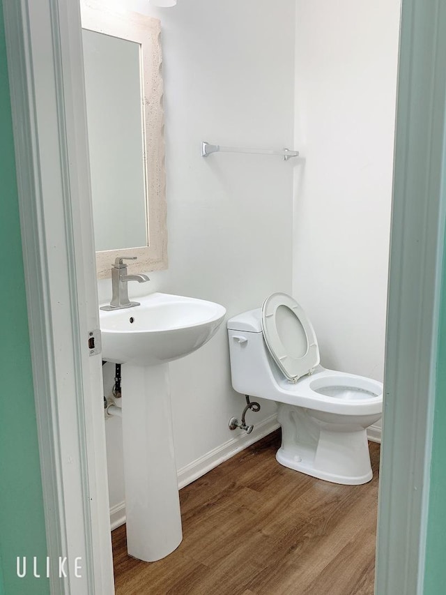 half bathroom with toilet, baseboards, and wood finished floors