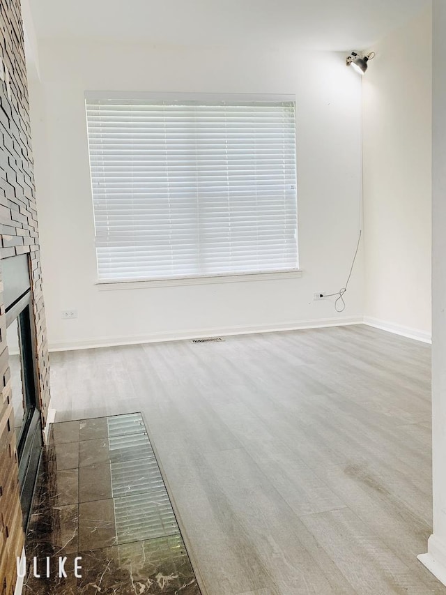 unfurnished living room featuring baseboards, a fireplace, visible vents, and wood finished floors