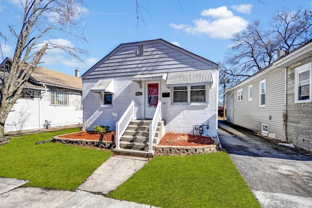 view of front of home with concrete block siding, aphalt driveway, and a front yard