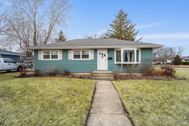 view of front of home featuring a front lawn and roof with shingles