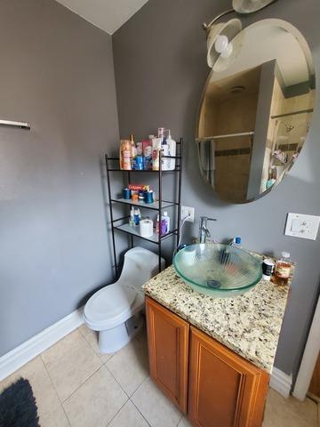 full bathroom with toilet, tile patterned flooring, baseboards, and vanity