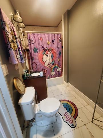 full bathroom featuring shower / bath combination with curtain, toilet, a sink, baseboards, and tile patterned floors