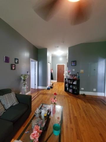 living room with a ceiling fan, lofted ceiling, baseboards, and wood finished floors