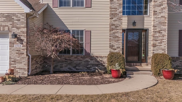 doorway to property featuring brick siding and an attached garage