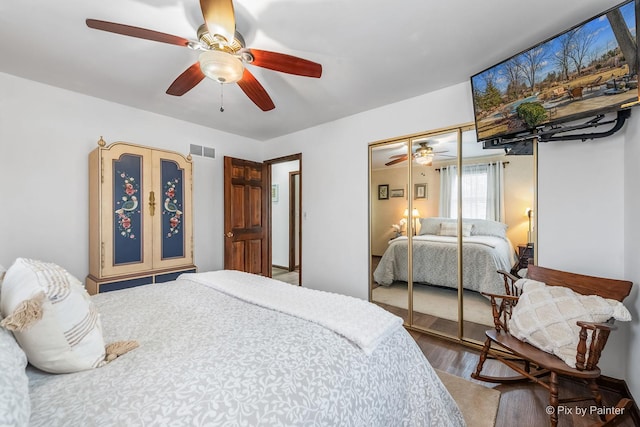 bedroom featuring a ceiling fan, a closet, visible vents, and wood finished floors