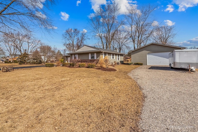 single story home with a garage, an outbuilding, and a front yard