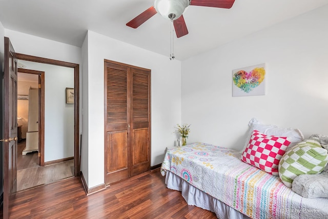 bedroom with ceiling fan, baseboards, dark wood finished floors, and a closet