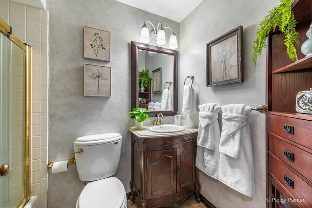 bathroom with a shower with door, vanity, and toilet