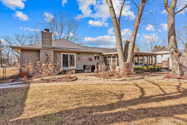 back of house with a sunroom, a chimney, fence, and a yard