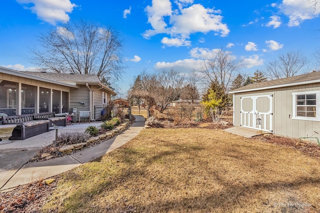 view of yard featuring a sunroom, a patio, an outdoor structure, and fence