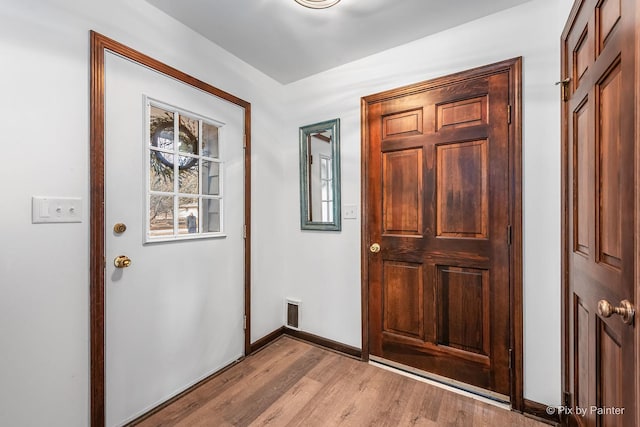 foyer entrance with light wood-type flooring, visible vents, and baseboards