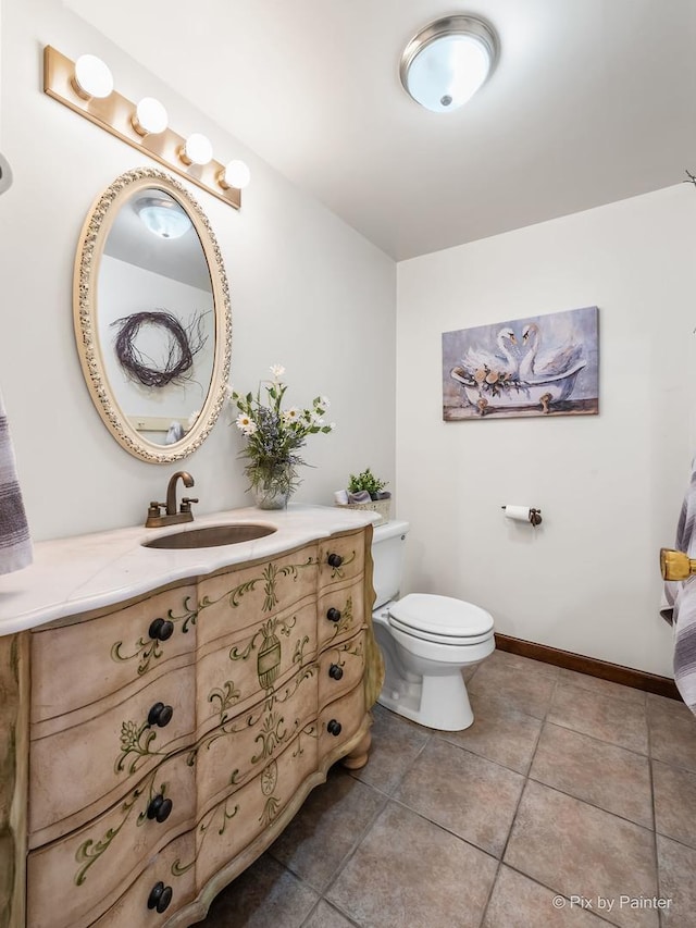 bathroom with toilet, tile patterned flooring, baseboards, and vanity