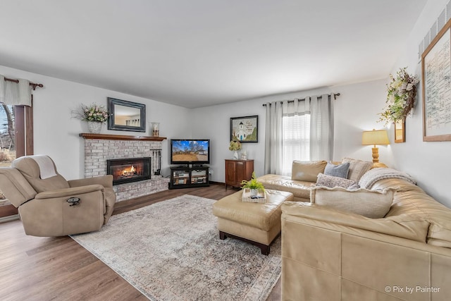 living room with a brick fireplace and wood finished floors