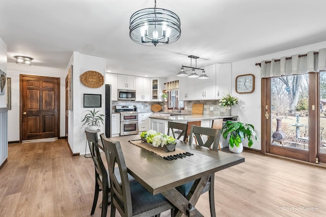 dining space with baseboards, light wood-style flooring, and an inviting chandelier