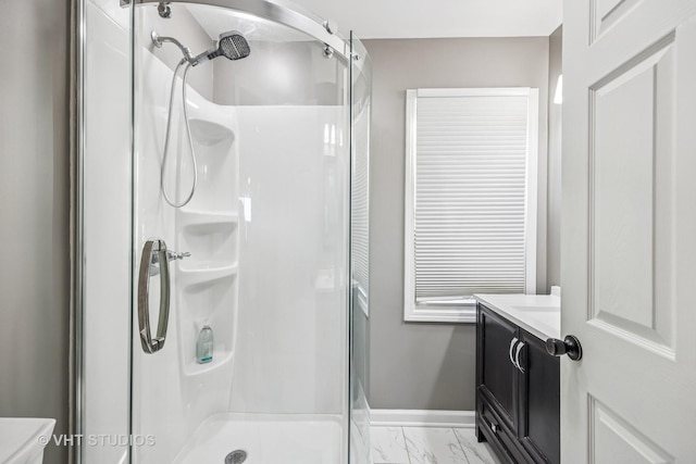 bathroom with marble finish floor, a shower stall, vanity, and baseboards