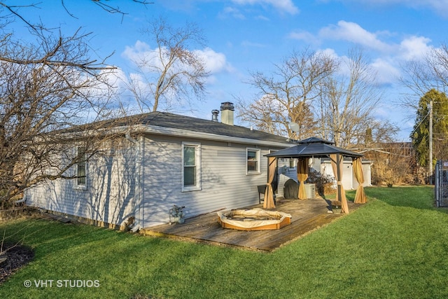 back of property featuring a wooden deck, a chimney, a lawn, and a gazebo