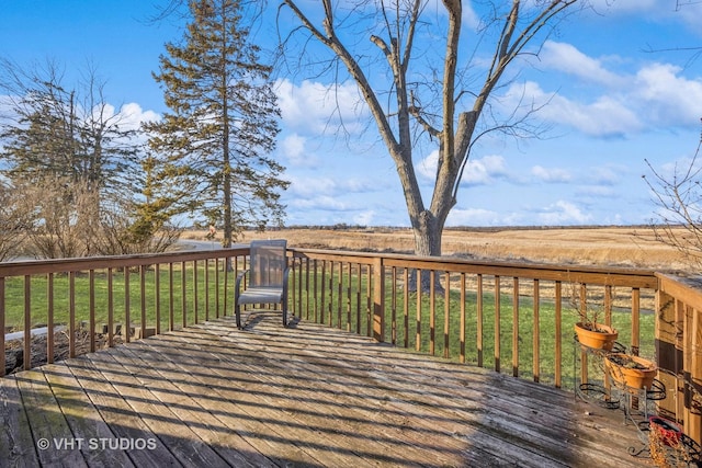 wooden terrace with a rural view and a lawn