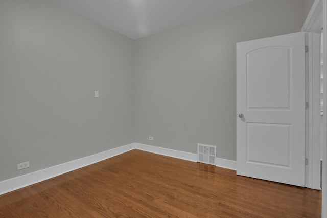 unfurnished room with wood finished floors, visible vents, and baseboards