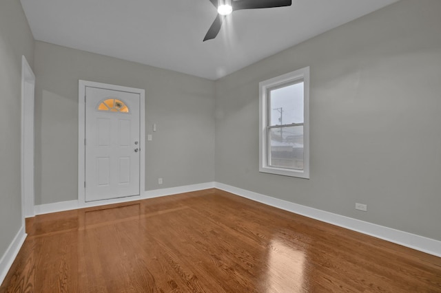 spare room with wood finished floors, a ceiling fan, and baseboards