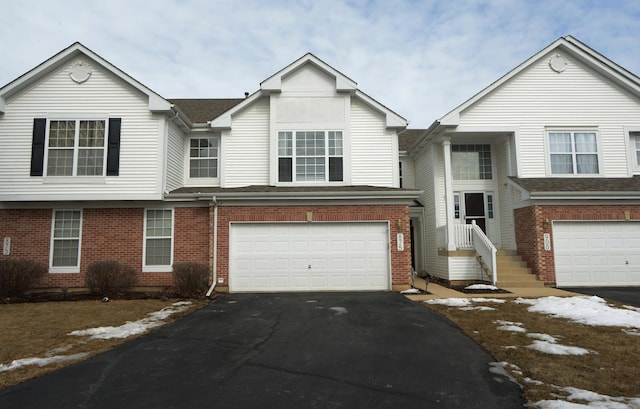 townhome / multi-family property featuring aphalt driveway, an attached garage, and brick siding