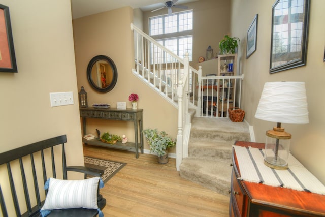 stairs with wood finished floors, a ceiling fan, and baseboards