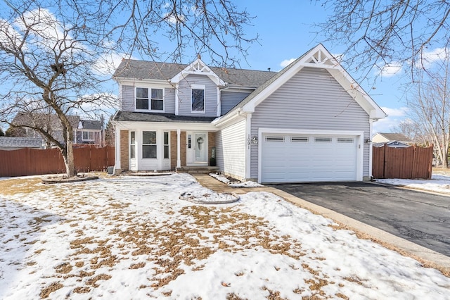 traditional home featuring aphalt driveway, fence, and an attached garage