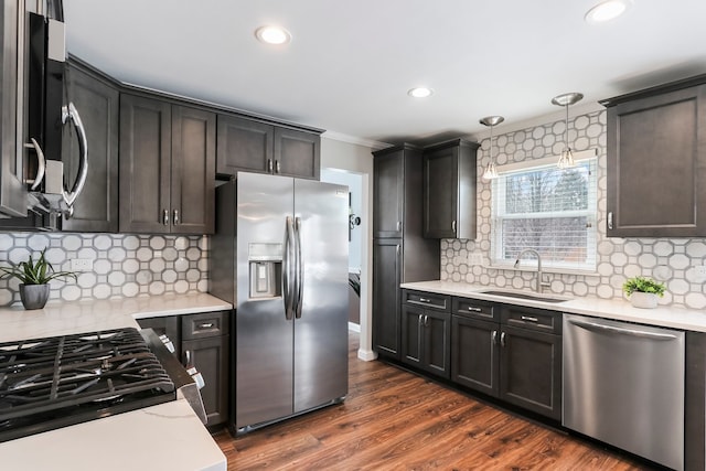 kitchen featuring dark wood-style flooring, a sink, appliances with stainless steel finishes, pendant lighting, and crown molding