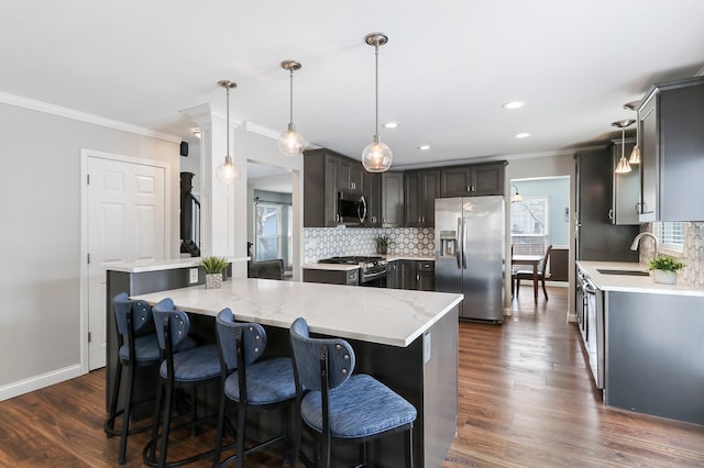 kitchen with decorative backsplash, dark wood finished floors, a kitchen island, appliances with stainless steel finishes, and ornamental molding