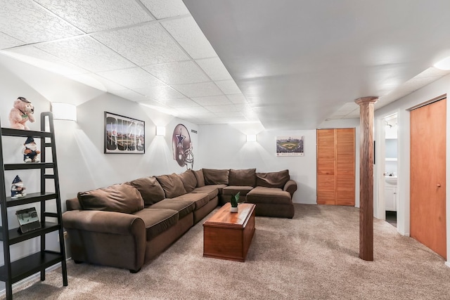 carpeted living room featuring a drop ceiling and ornate columns