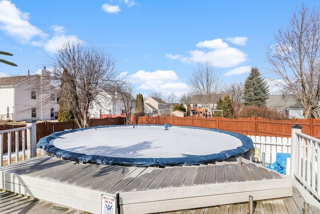 wooden terrace with a trampoline and a fenced backyard