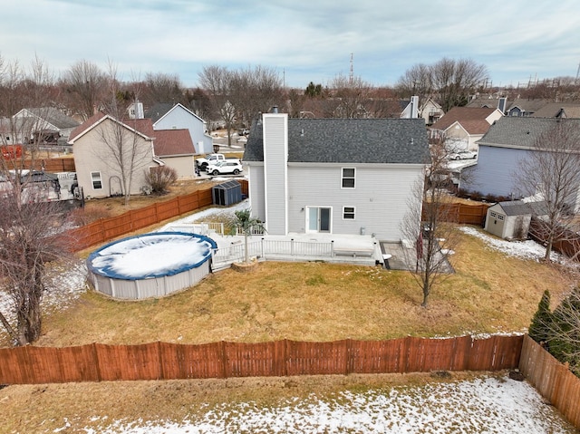 rear view of house with a fenced backyard, a chimney, a residential view, and a fenced in pool