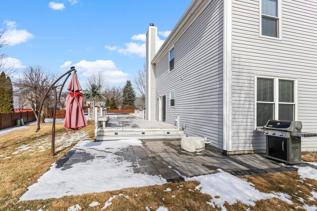 snow covered back of property with a storage shed, a fenced backyard, a chimney, roof with shingles, and an outdoor structure