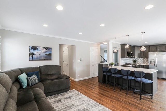 kitchen with dark brown cabinetry, stainless steel appliances, dark wood-style flooring, a sink, and backsplash