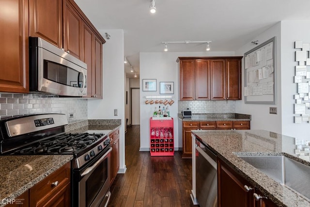 kitchen with tasteful backsplash, appliances with stainless steel finishes, dark wood-type flooring, and light stone counters