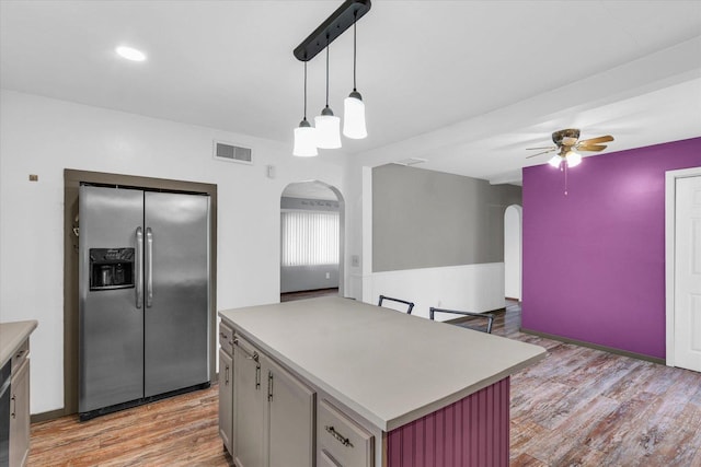kitchen featuring stainless steel fridge with ice dispenser, visible vents, ceiling fan, and arched walkways