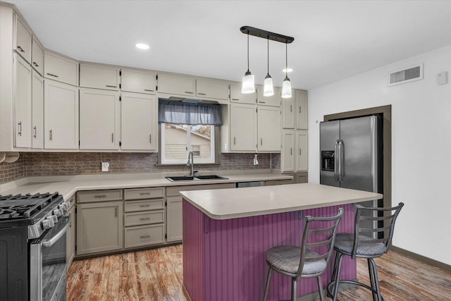 kitchen with tasteful backsplash, light countertops, visible vents, appliances with stainless steel finishes, and a sink
