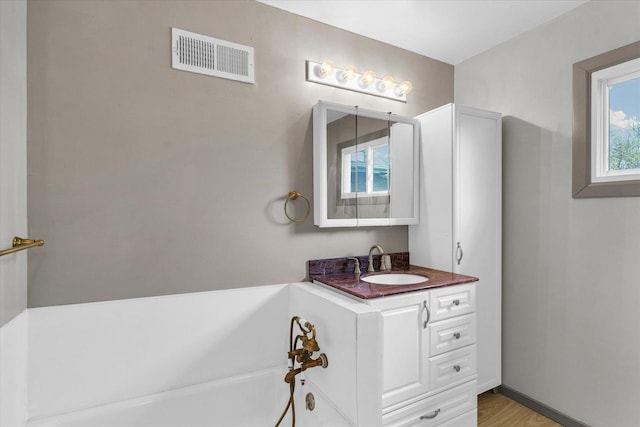 full bath with a bathing tub, visible vents, vanity, and wood finished floors