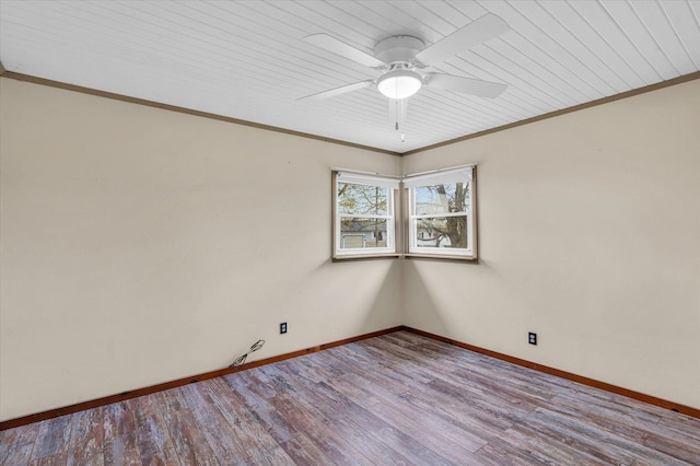 spare room featuring crown molding, wood finished floors, ceiling fan, and baseboards
