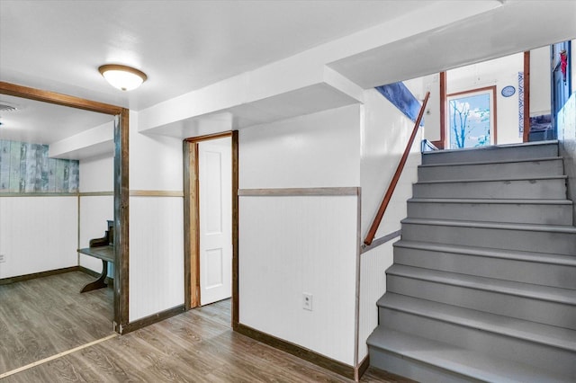 interior space with wood finished floors, stairway, and a wainscoted wall