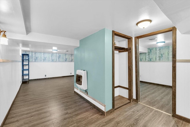 interior space with visible vents, baseboards, heating unit, wainscoting, and wood finished floors