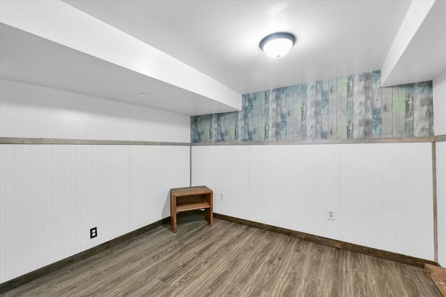 basement featuring wainscoting, baseboards, and wood finished floors