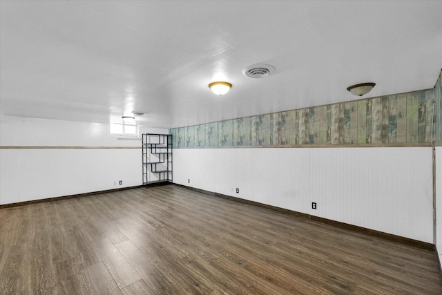 unfurnished room with wainscoting, visible vents, baseboards, and wood finished floors